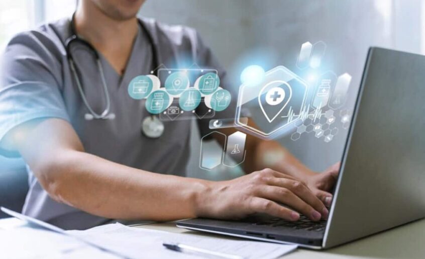 A healthcare professional uses a laptop with virtual medical icons floating above the screen