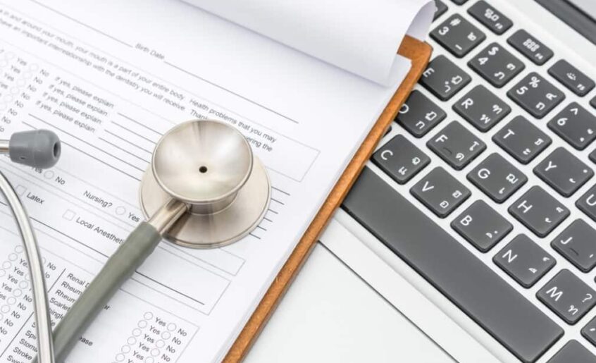 a stethoscope on medical form sheet and laptop keyboard near it