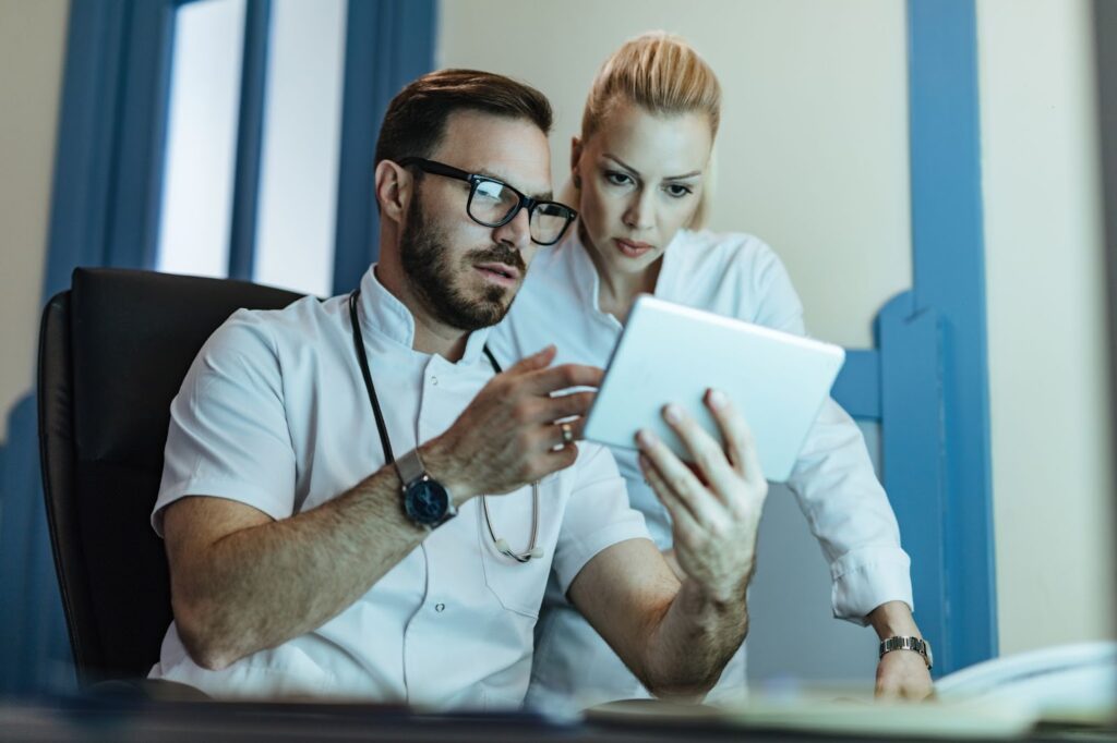 Two healthcare workers analyzing medical records on touchpad